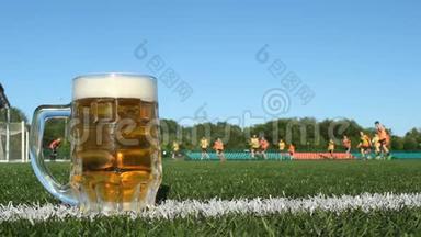 一杯啤酒站在足球场上的草地上，球员们踢足球